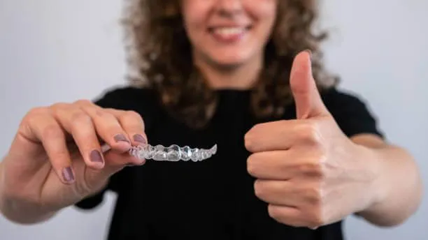 a person holding an Invisalign with holding up a thumbs up