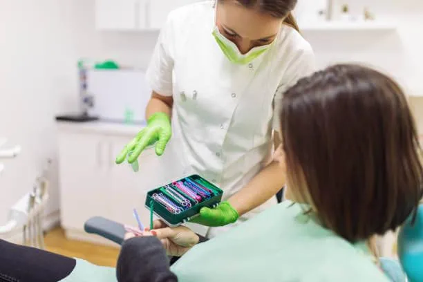 a woman sitting on a dental chair while choosing a color for her braces