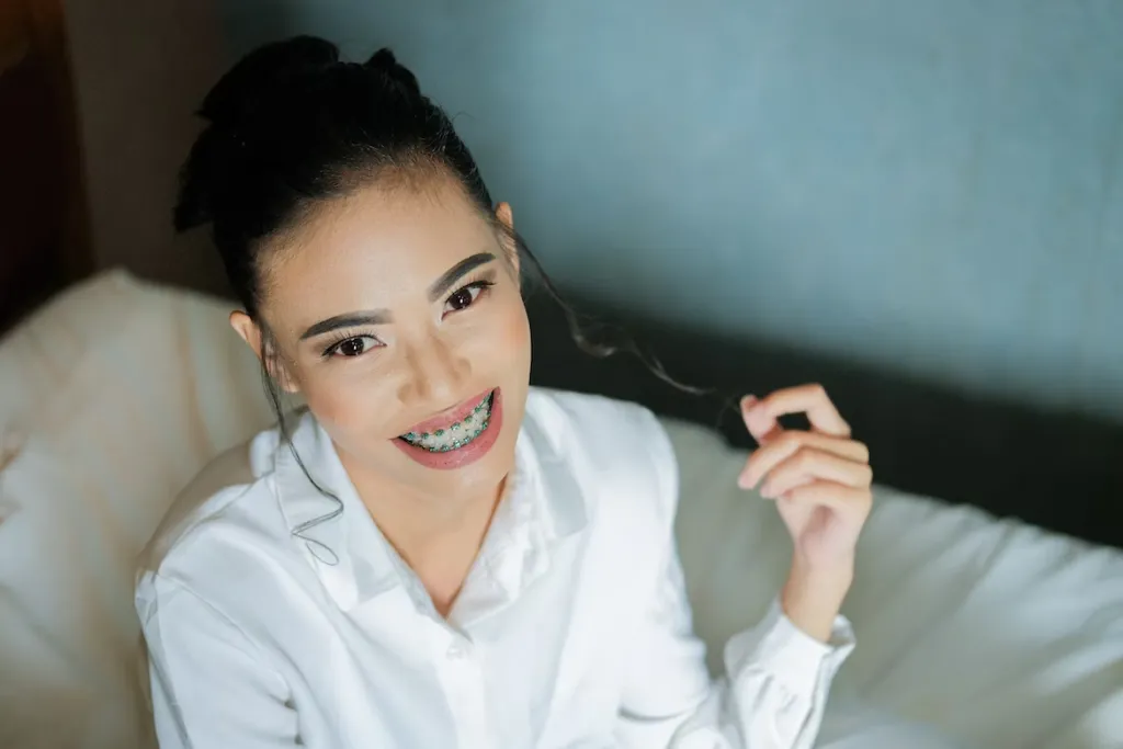 a woman with braces smiling while holding her hair