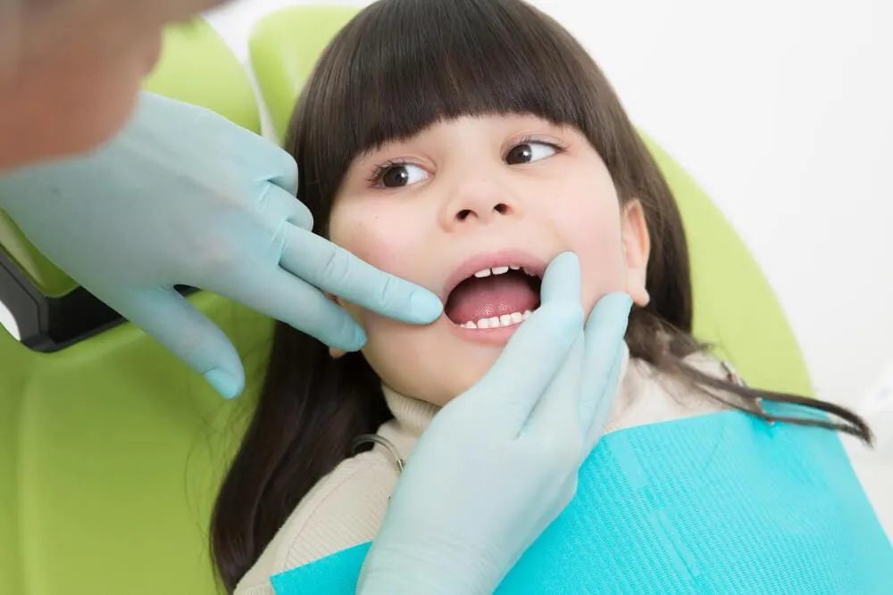 a kid getting her teeth examined by a dentist