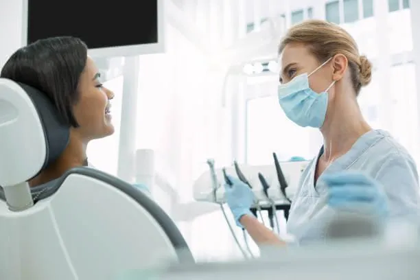 a person wearing a mask and gloves talking to a dentist