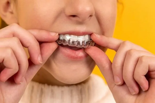 a person wearing her Invisalign against the yellow background