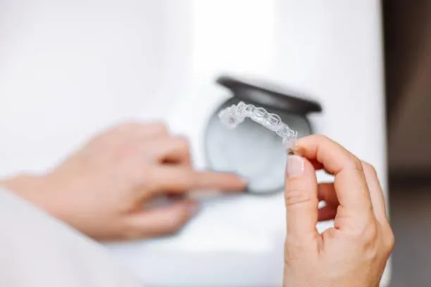 a person's hand holding a clear aligner